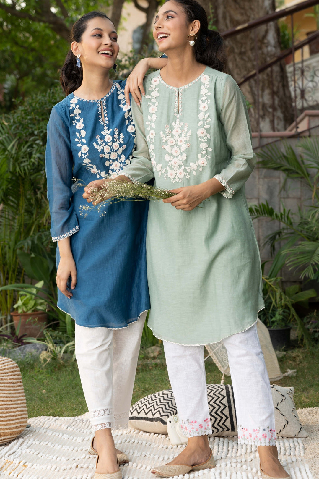 Woman wearing teal embroidered tunic with intricate embroidery and sheer long sleeves