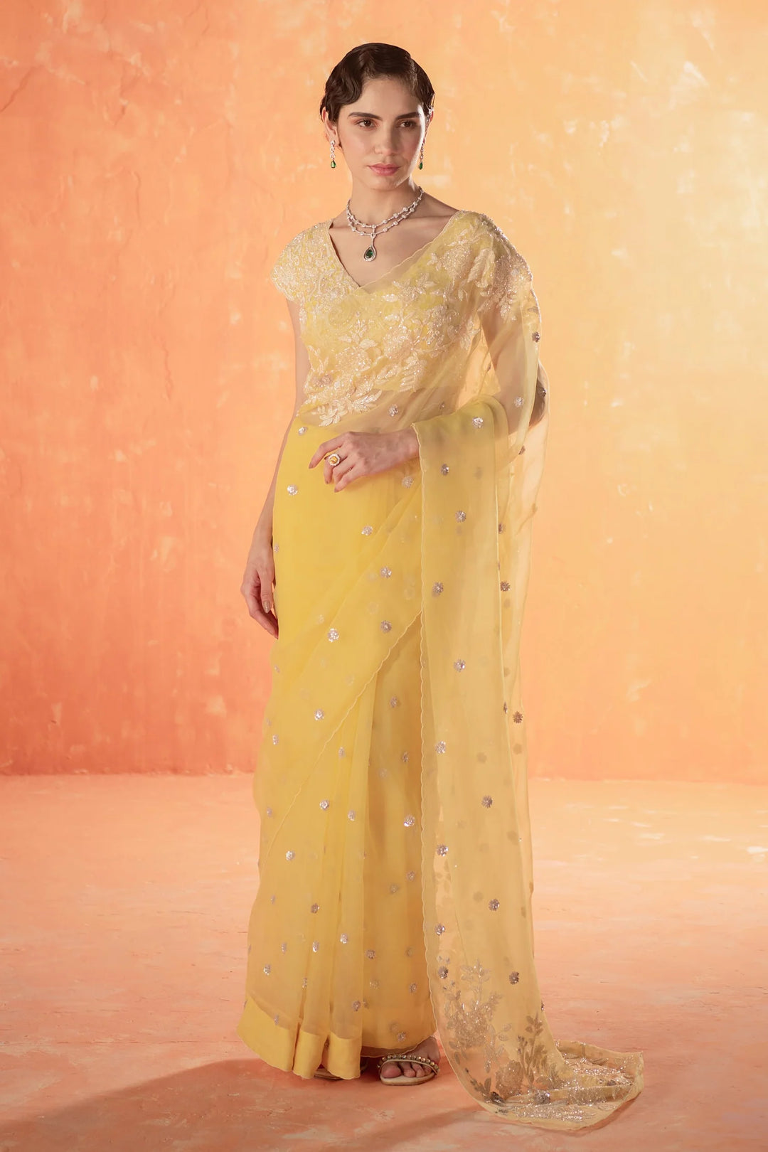 Woman wearing pastel yellow embroidered saree with sheer blouse, elegant look for Haldi ceremony