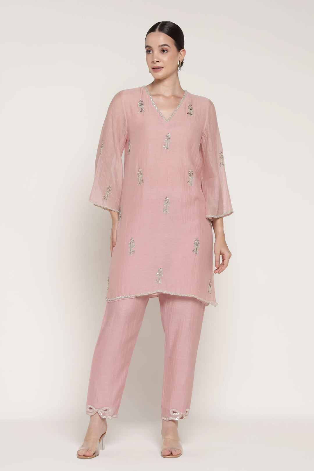 Woman wearing a pink outfit with floral patterns on a white background