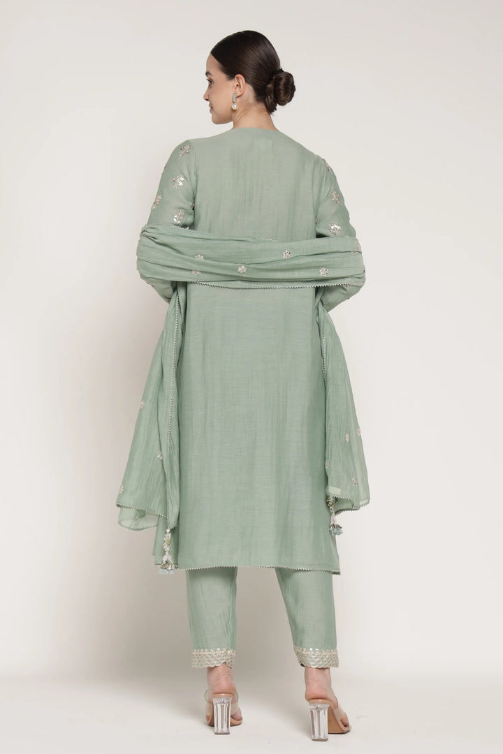 Woman wearing a light green traditional outfit with a matching dupatta on a white background