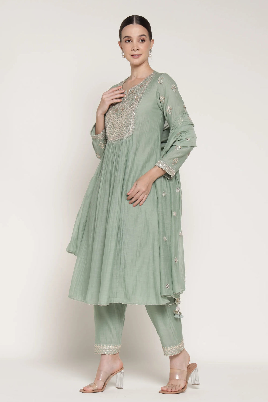 Woman wearing a light green traditional outfit with a plain background