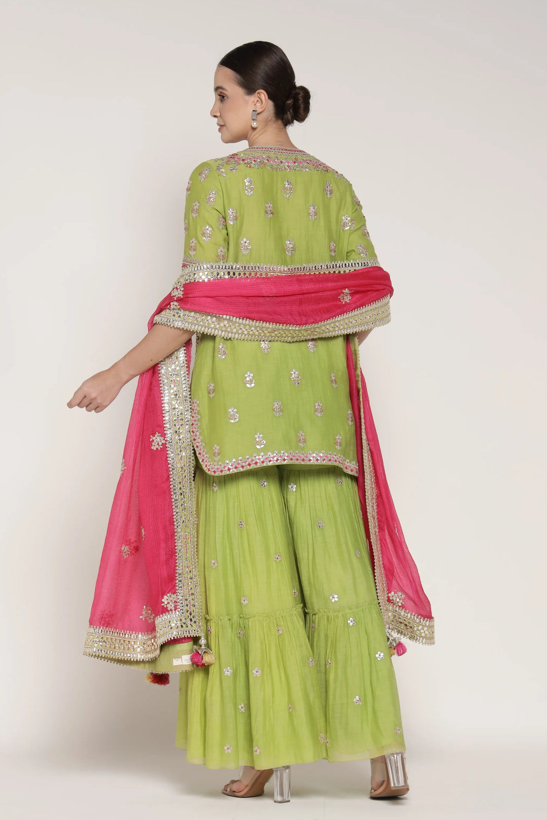 Woman wearing a green and pink traditional outfit with a white background