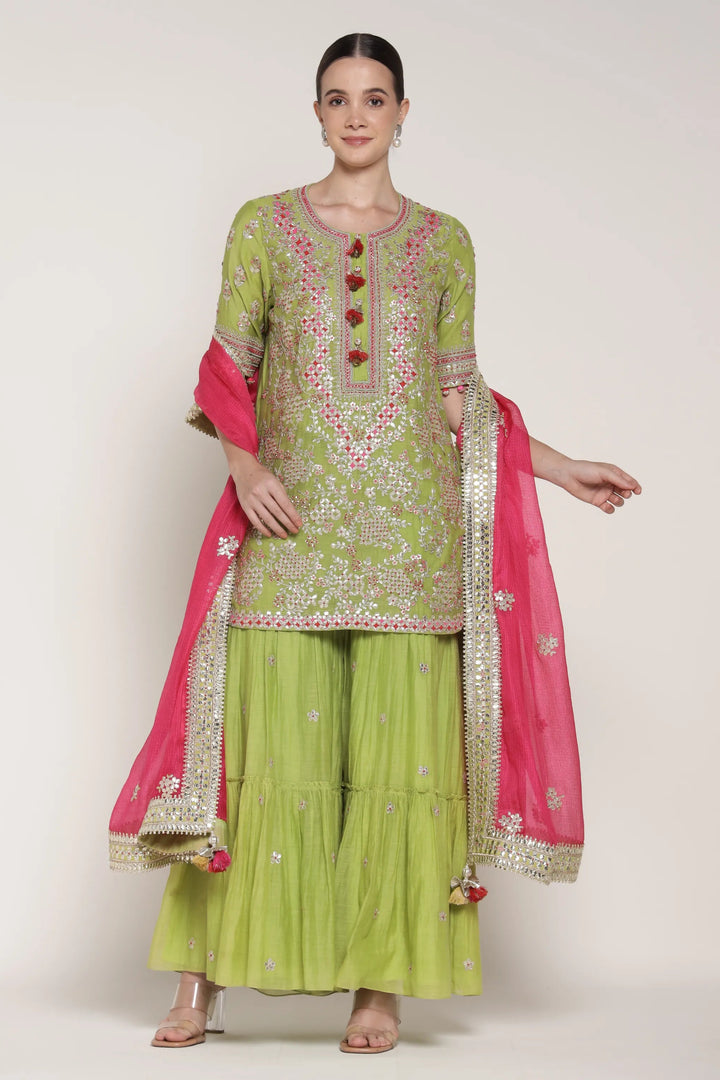 Woman wearing a green and pink traditional outfit with embroidery on a white background