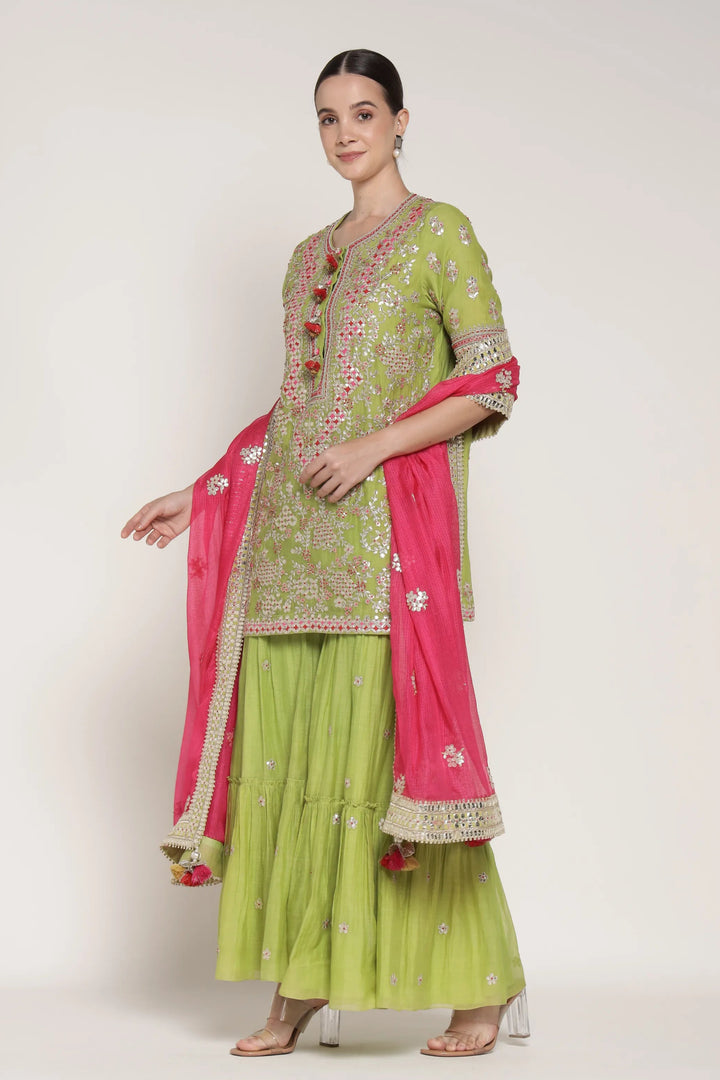 Woman wearing a green and pink traditional outfit on a white background