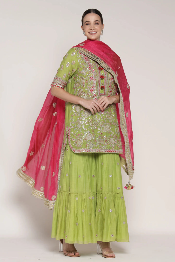 Woman wearing a green and pink traditional outfit on a white background