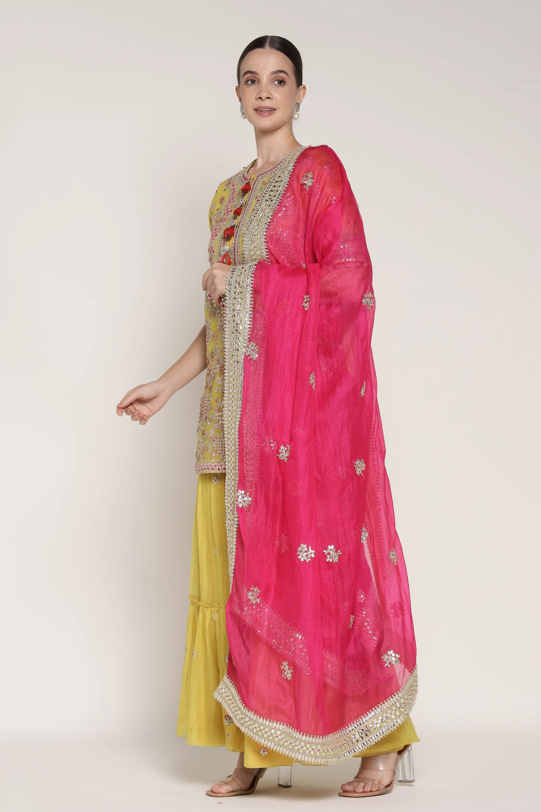 Woman wearing a yellow outfit with a pink embroidered dupatta on a white background