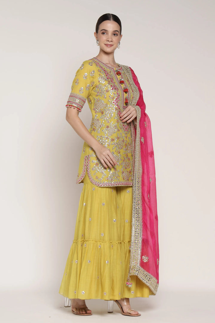 Woman wearing a yellow traditional outfit with pink dupatta on a white background