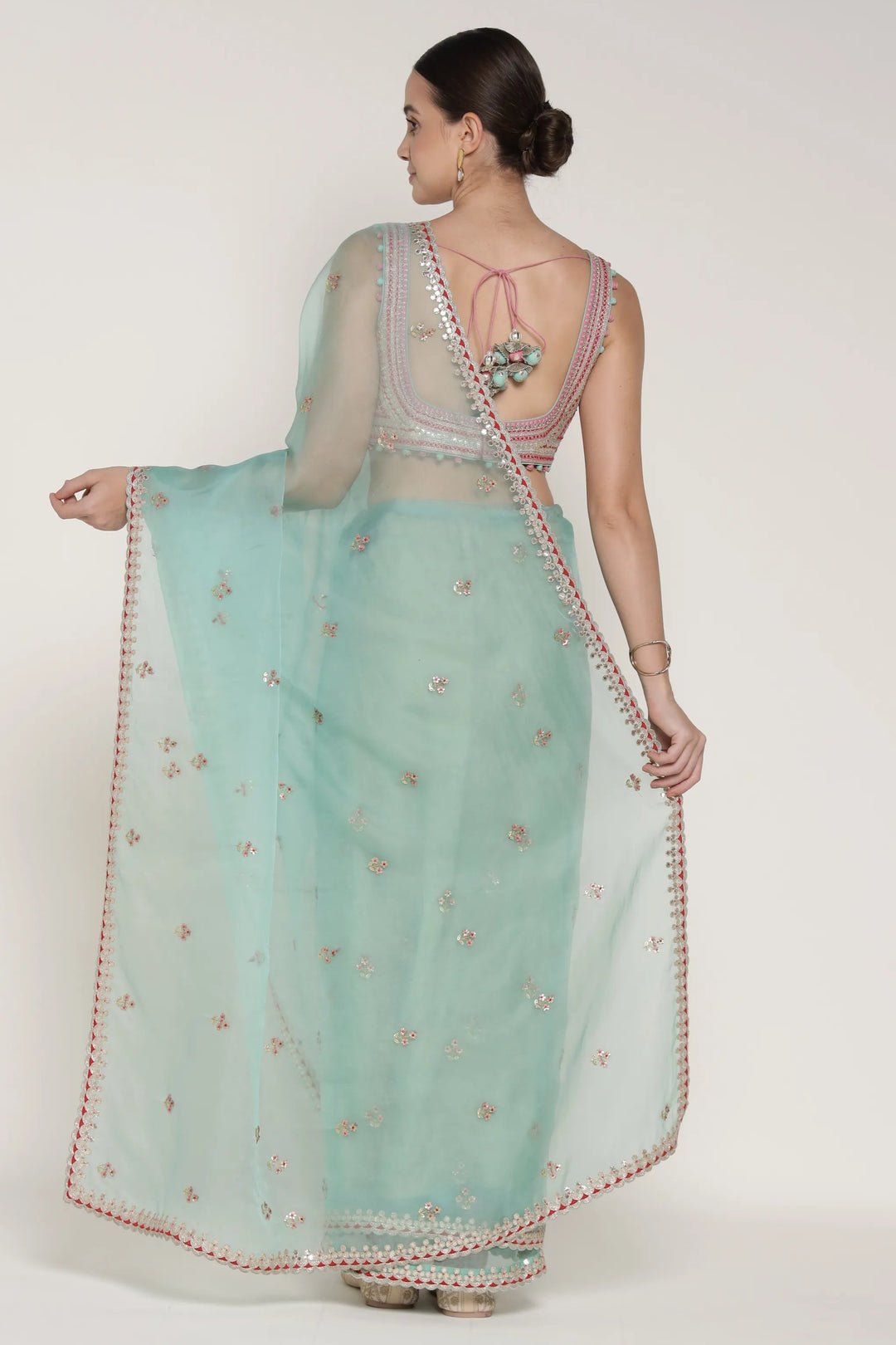 Woman wearing a light blue saree with a white blouse on a white background