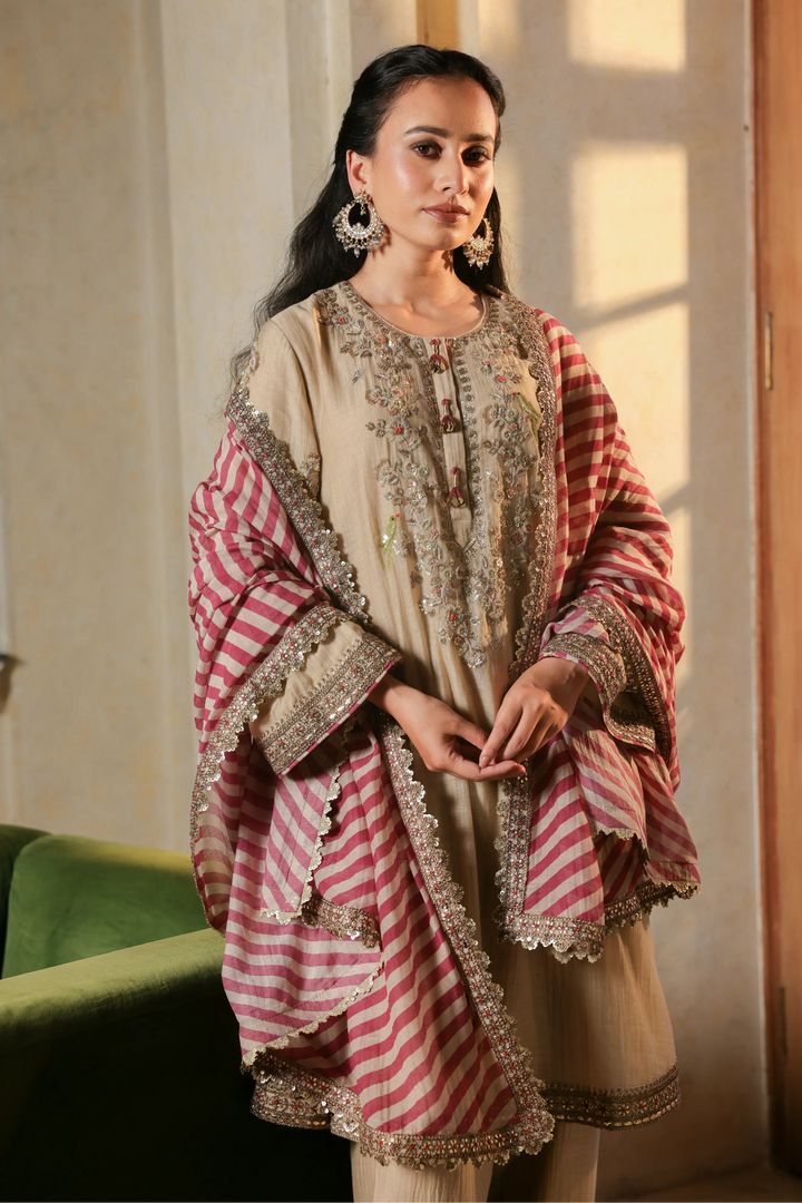 Woman wearing a traditional outfit with a red and white striped shawl in a softly lit room.