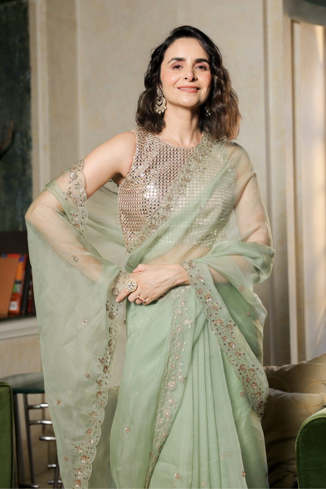 Woman in a light green saree with silver embellishments in an indoor setting.