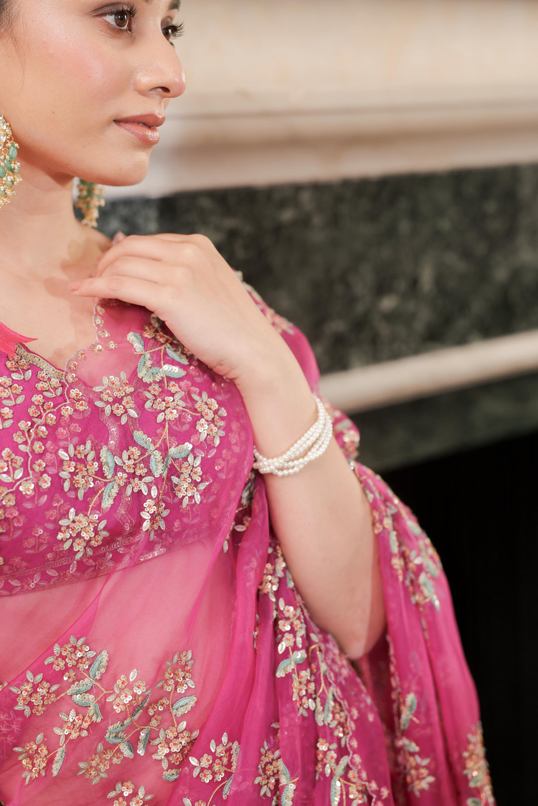 Woman wearing a pink saree with floral patterns indoors