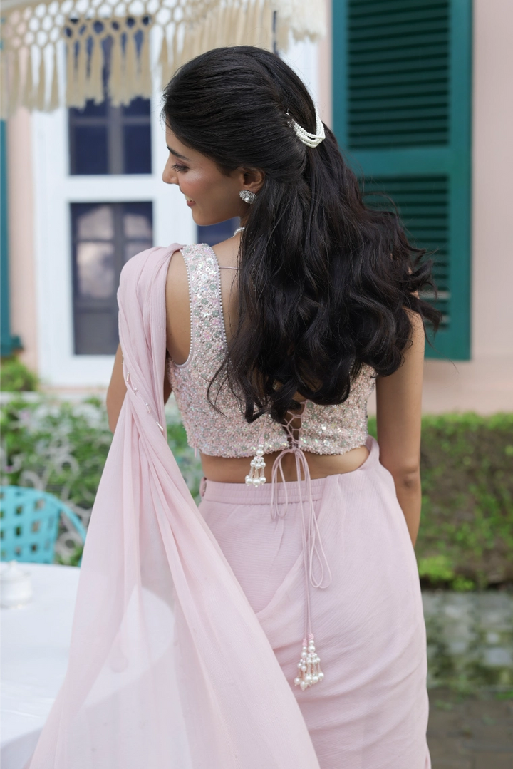 Woman in a light pink traditional outfit with a long hair braid, standing outdoors.