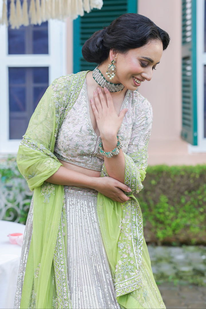 Woman in a light green and white traditional outfit standing outdoors.