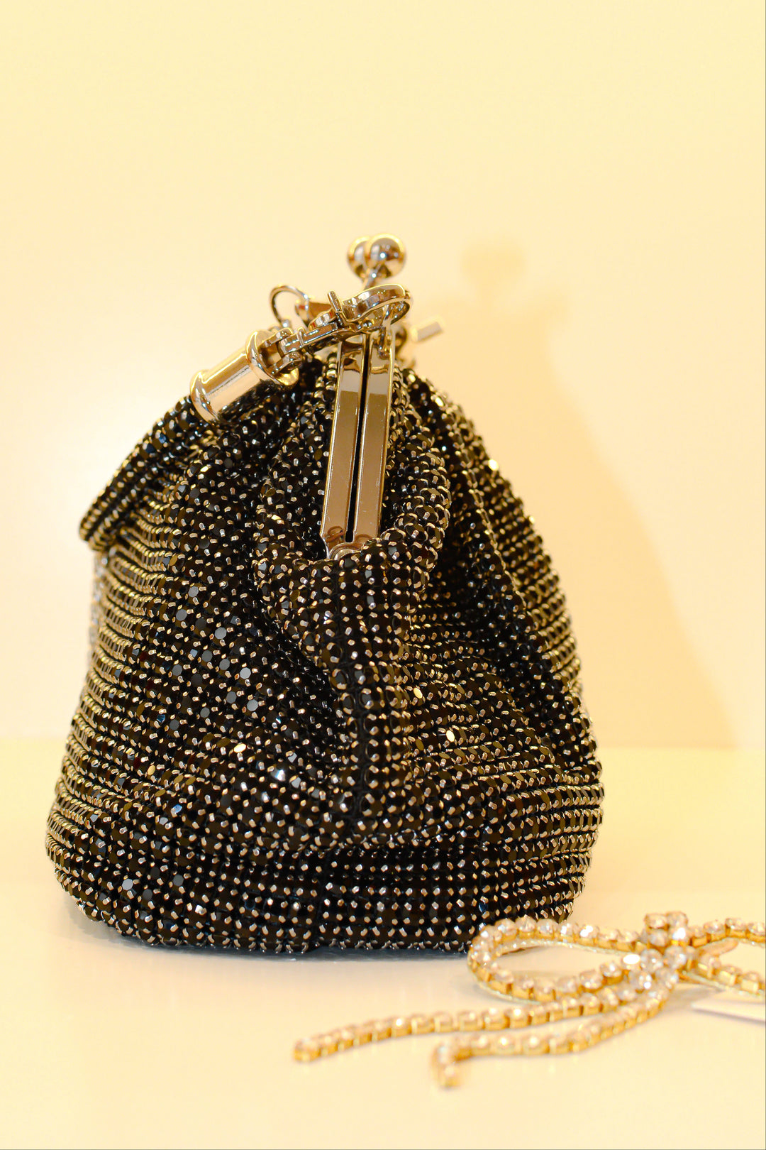 Black beaded handbag with gold accents on a beige background