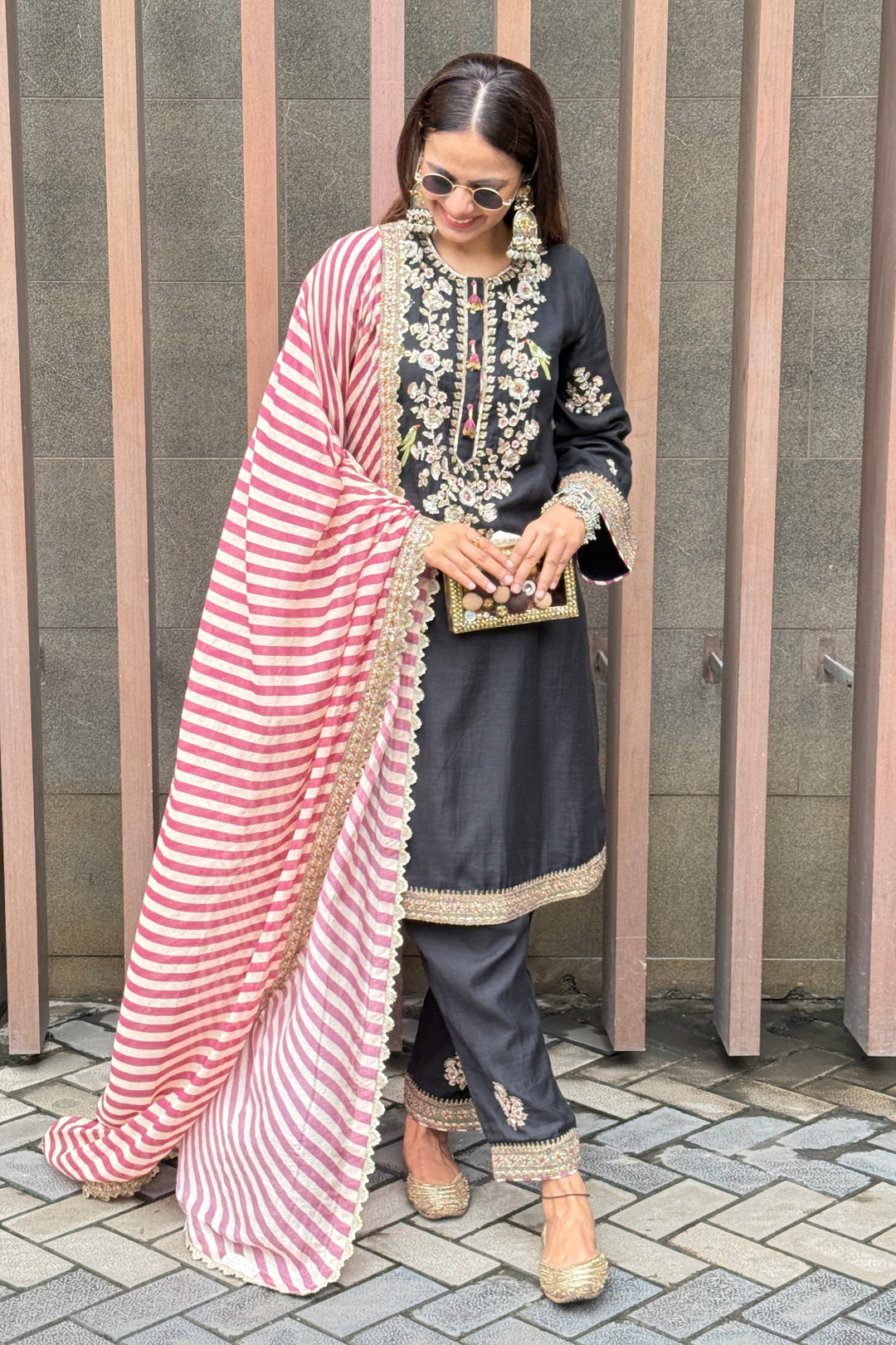 Person wearing a traditional outfit with a red and white striped shawl on a staircase.