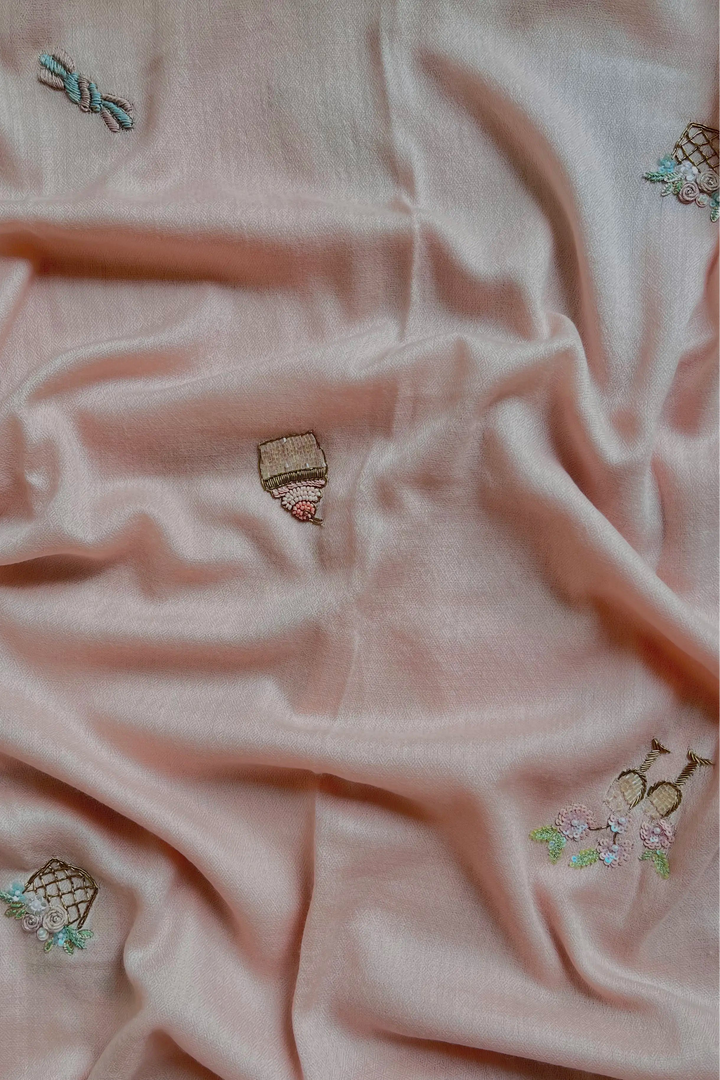Pink fabric with embroidered designs on a textured surface