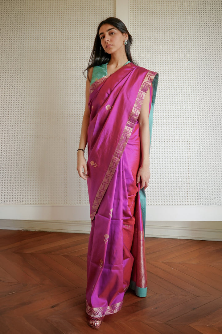 Woman wearing a pink saree with a green blouse against a neutral background
