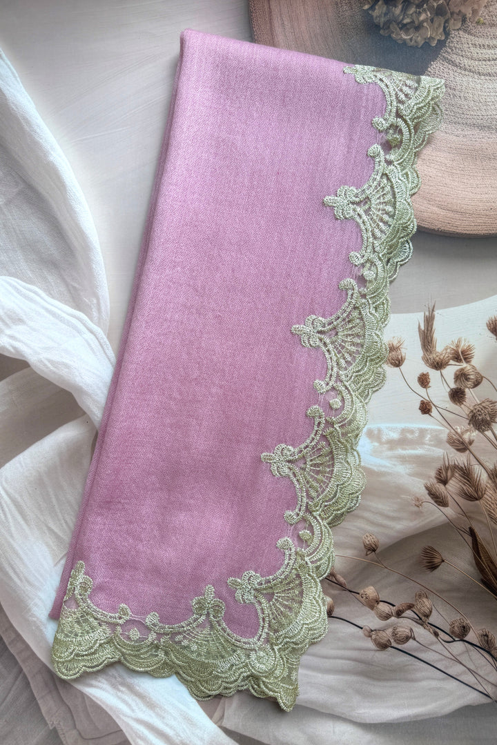 Pink fabric with green lace trim on a soft background