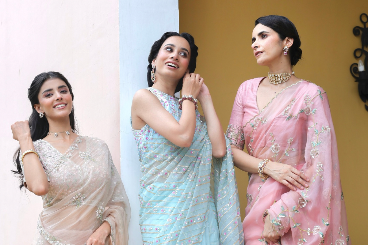 Three women in sarees posing against different colored backgrounds