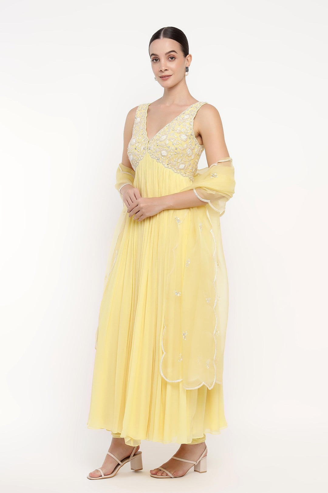 Woman wearing a yellow dress with floral patterns on a white background