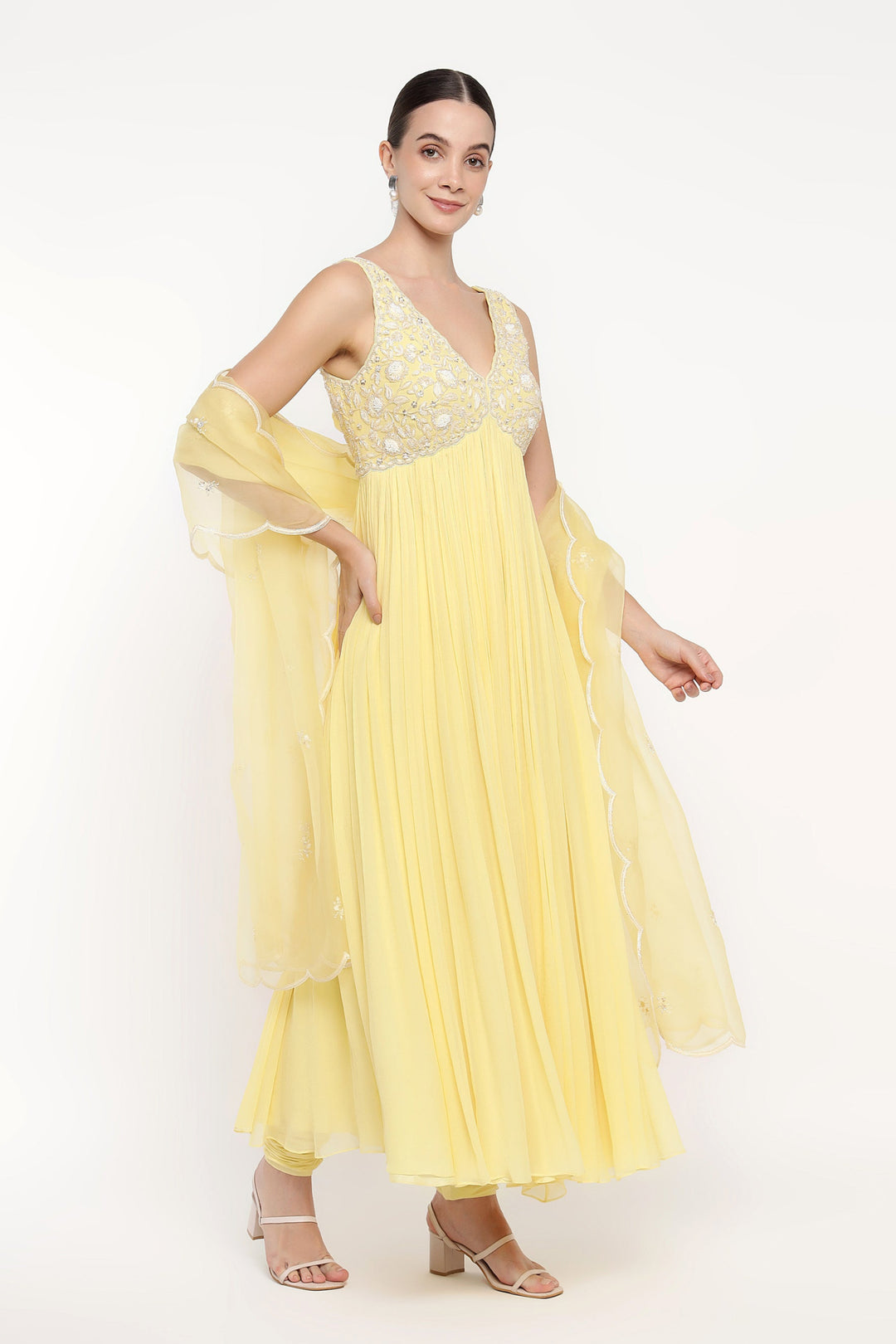 Woman wearing a yellow dress with floral embellishments on a white background