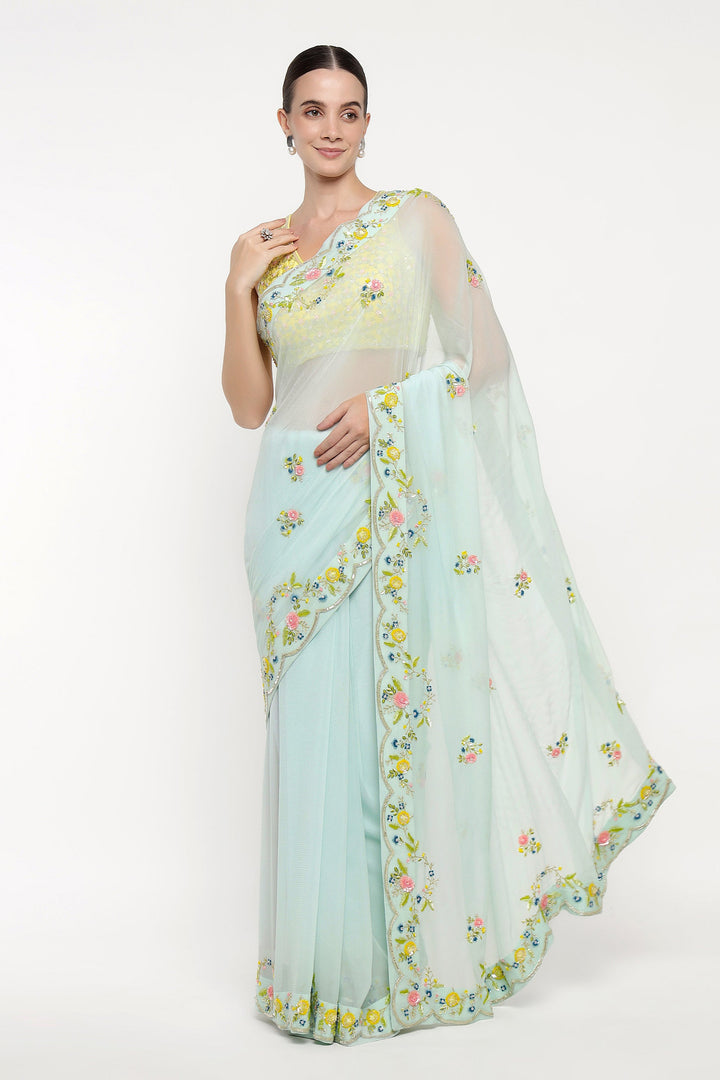 Woman wearing a light blue saree with floral patterns on a white background