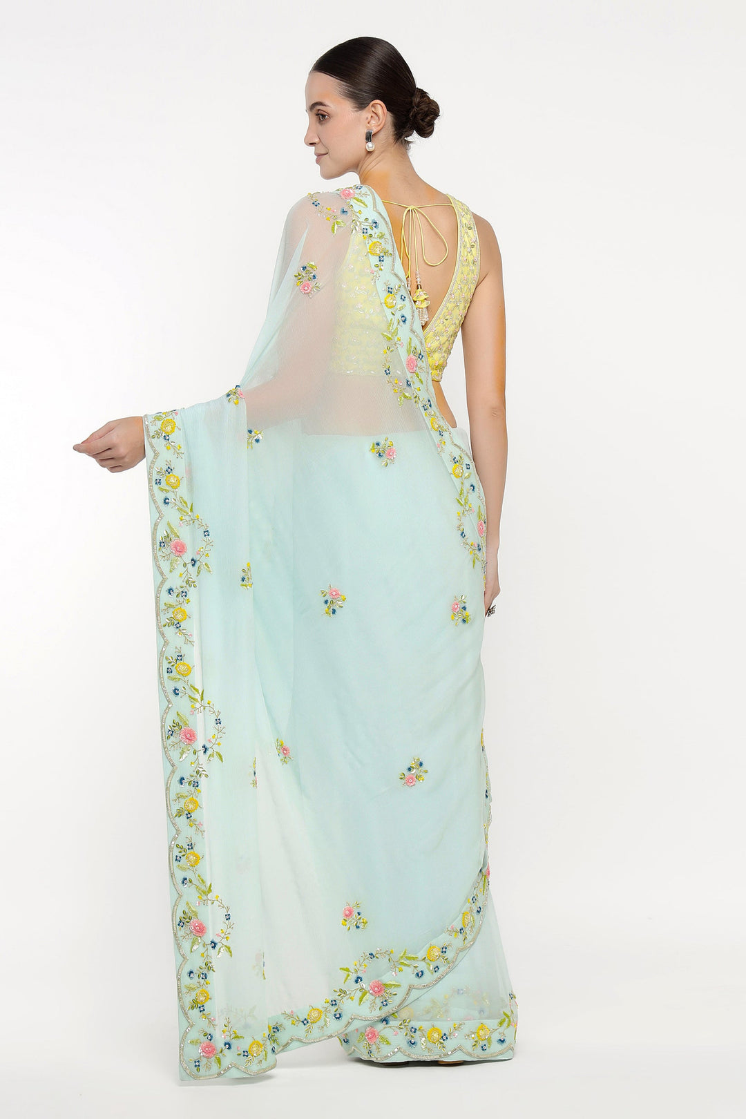 Woman wearing a light blue saree with floral patterns on a white background