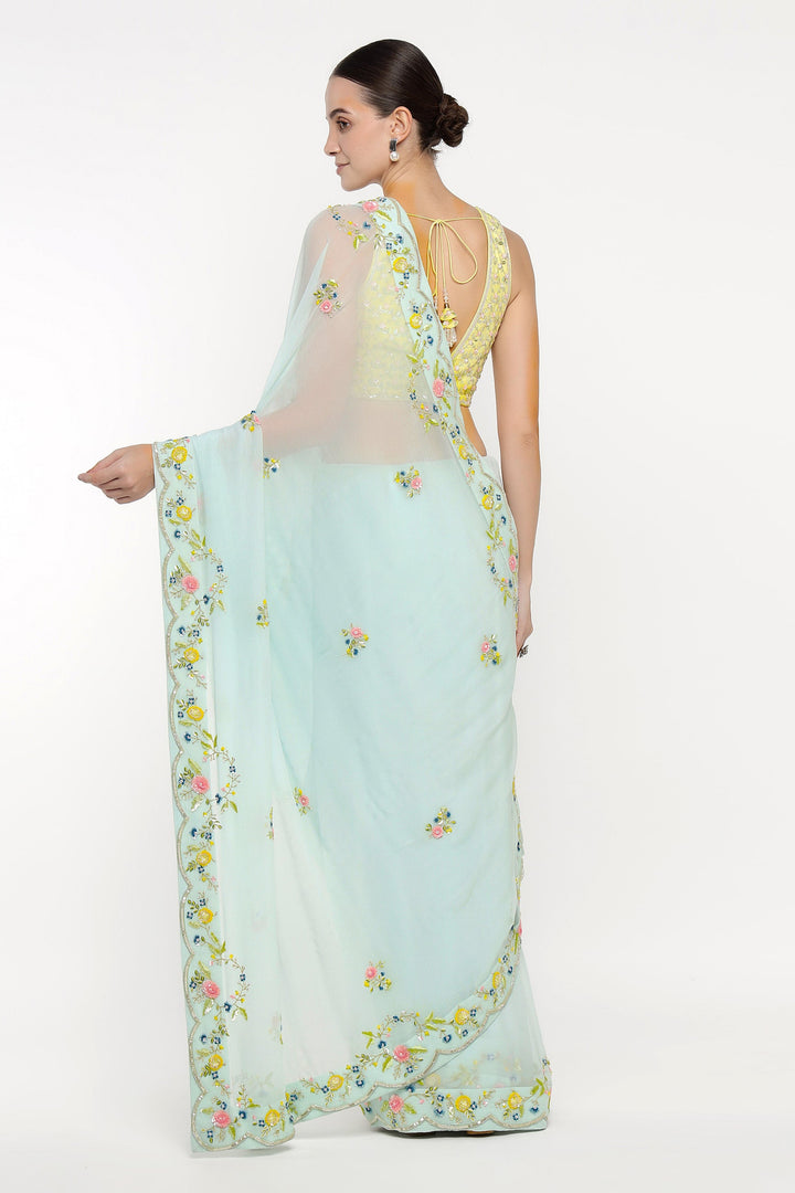 Woman wearing a light blue saree with floral patterns on a white background