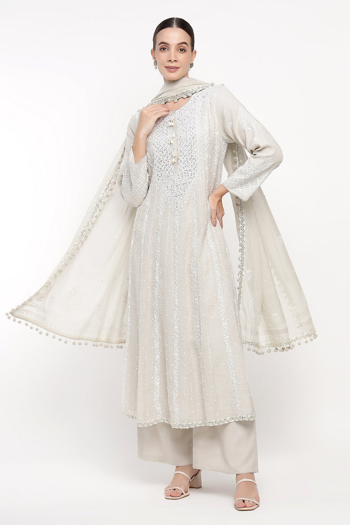 Woman wearing a white traditional outfit with a matching dupatta on a white background