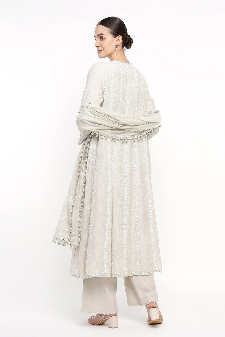 Woman wearing a light-colored traditional outfit with a scarf on a white background