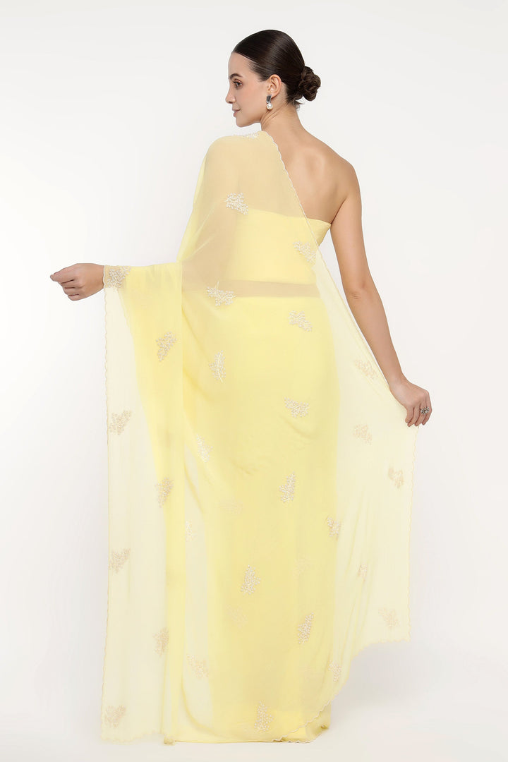 Woman wearing a light yellow one-shoulder dress with a sheer overlay on a white background