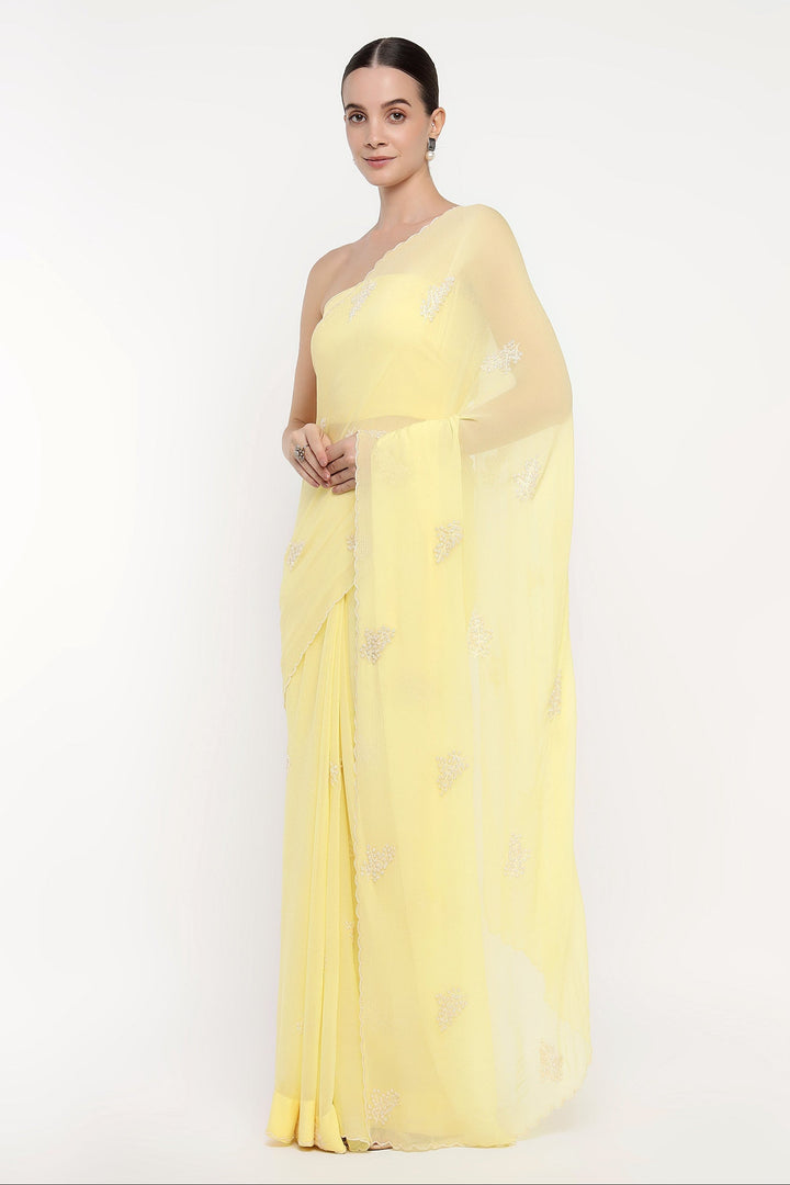 Woman wearing a light yellow saree with a subtle pattern on a white background