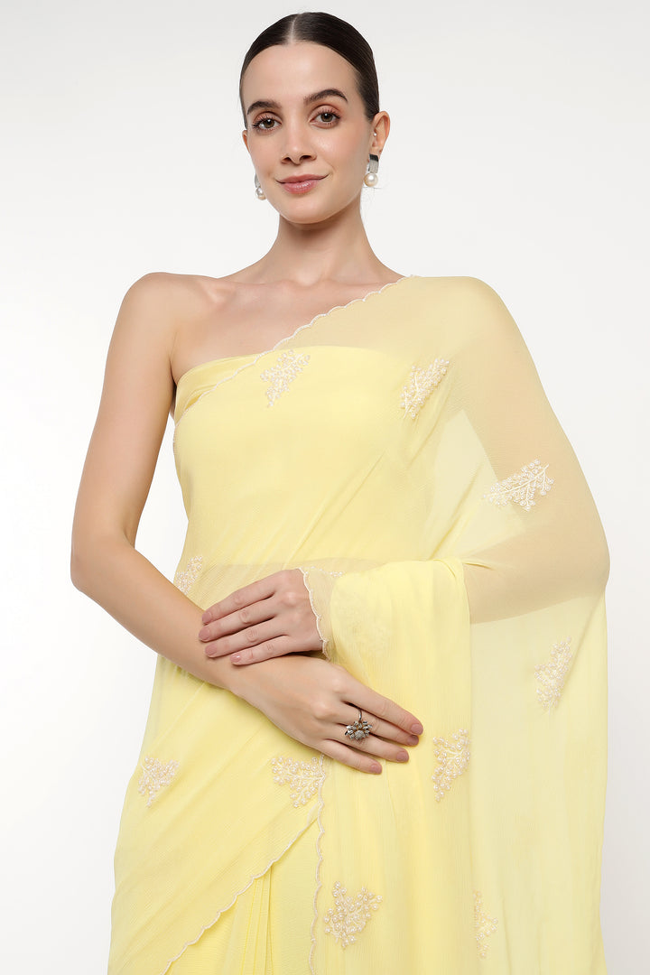 Woman wearing a light yellow saree with floral patterns on a white background