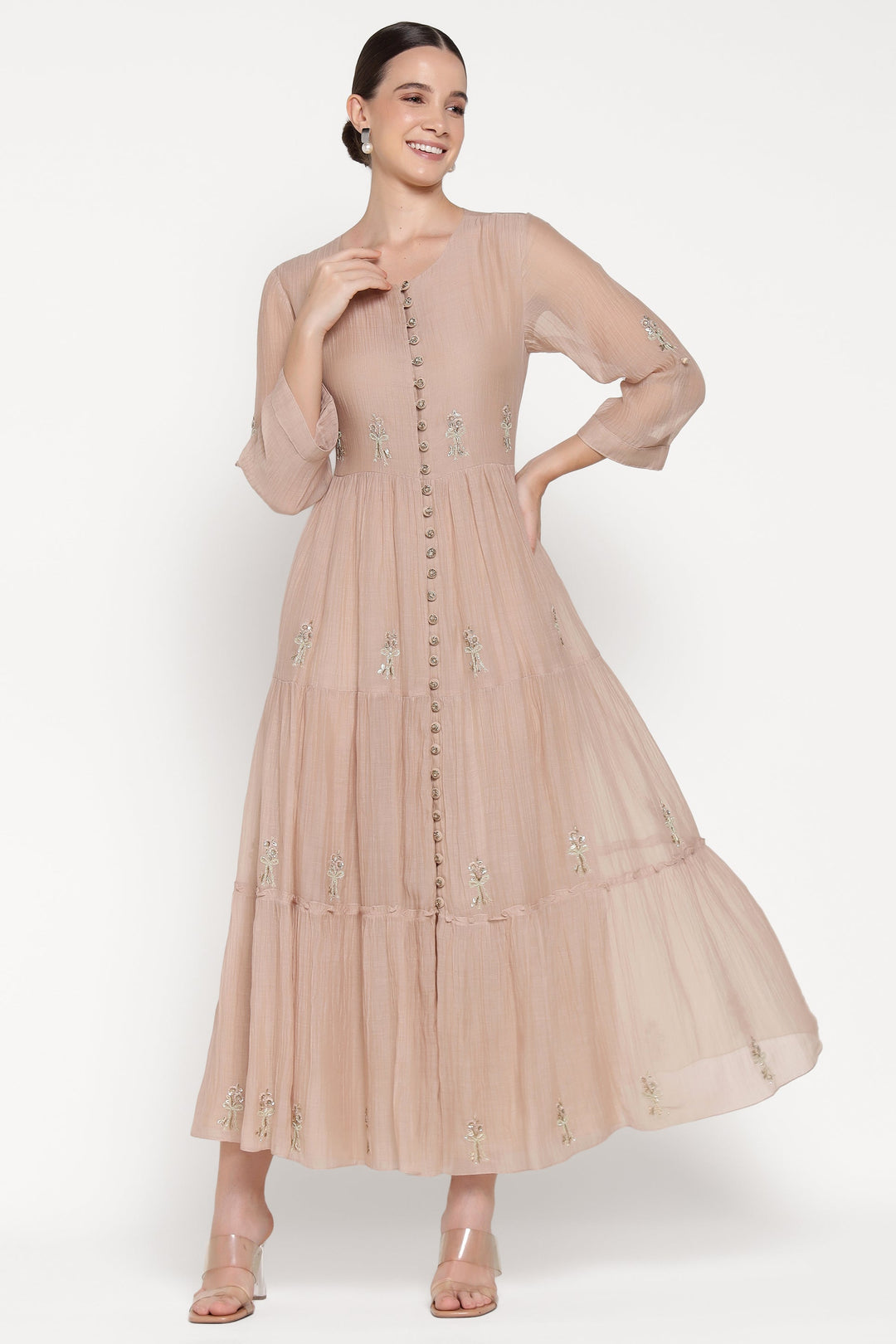 Woman wearing a beige dress with floral embroidery on a white background