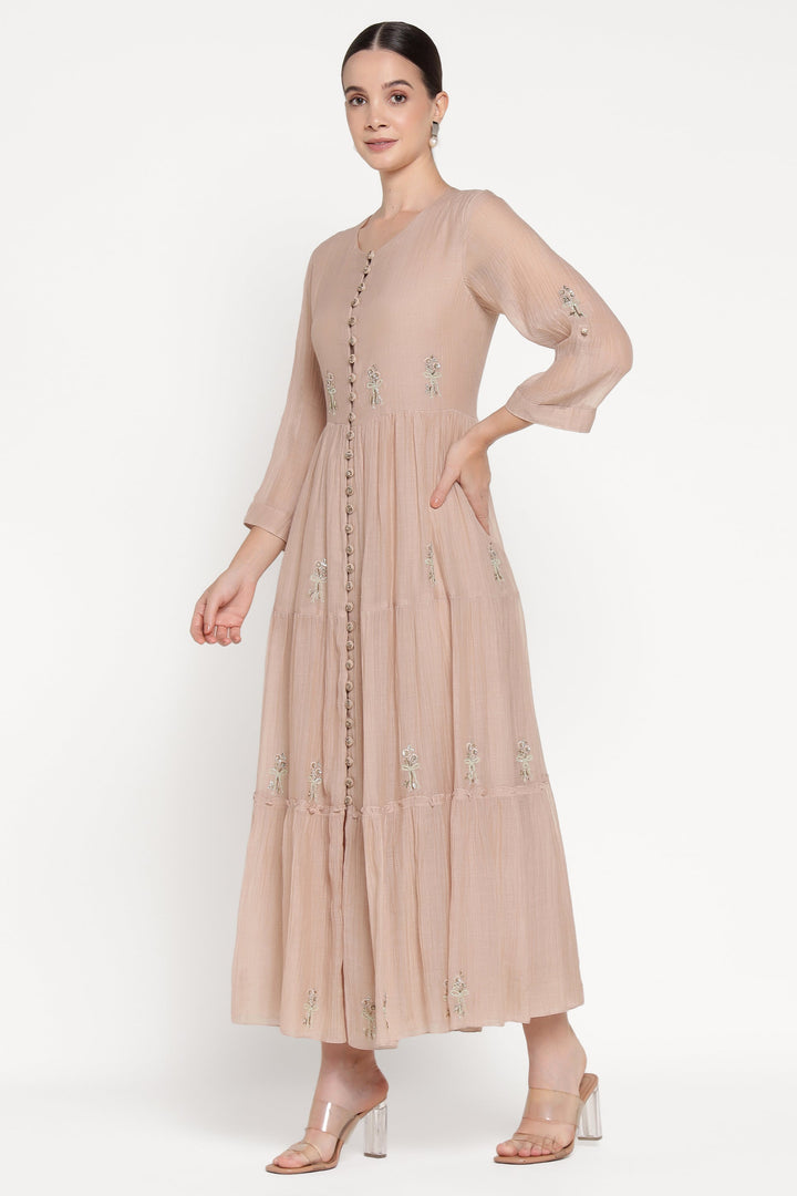 Woman wearing a beige dress with floral embellishments on a white background