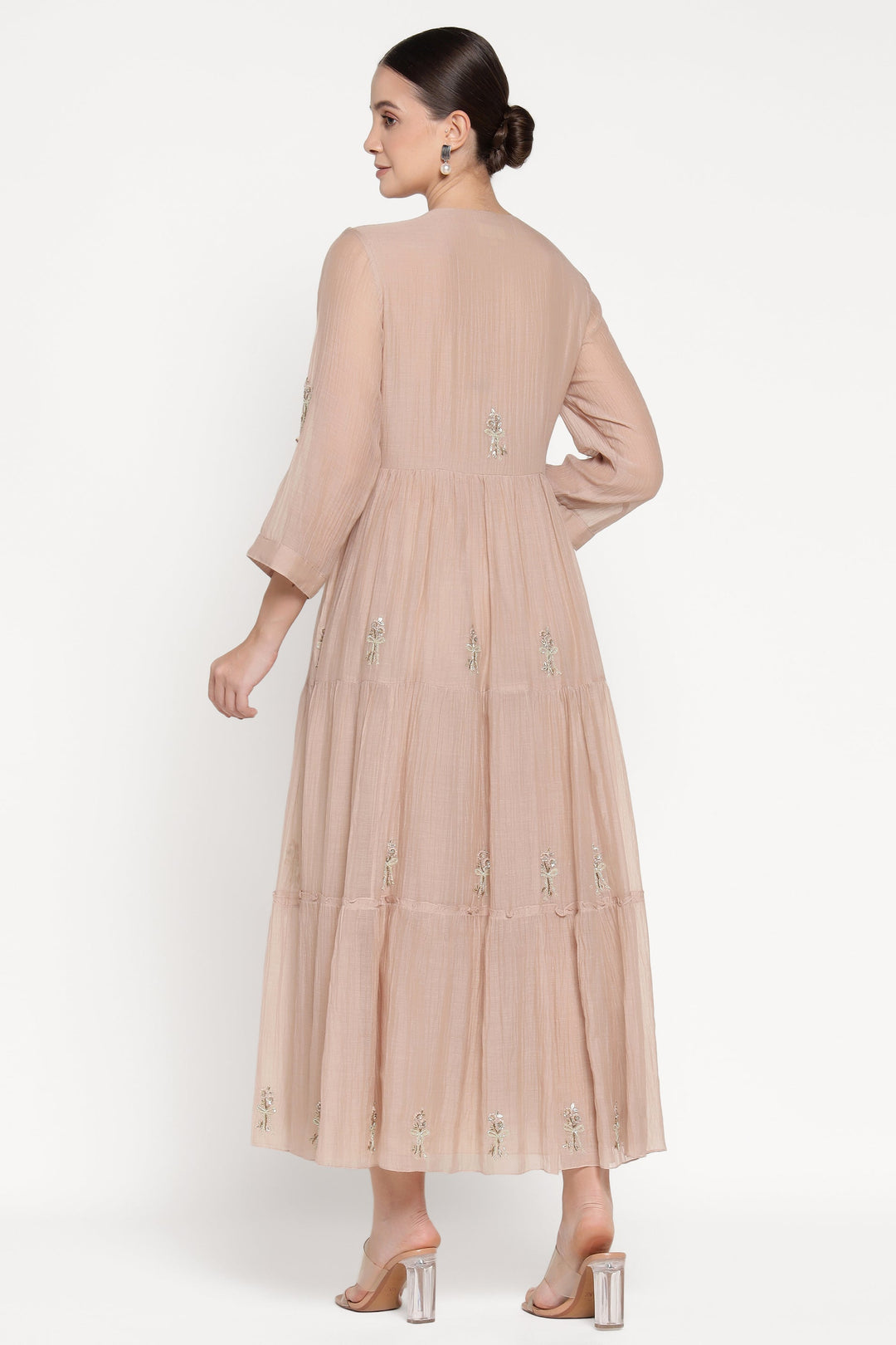 Woman wearing a beige dress with floral embroidery on a white background