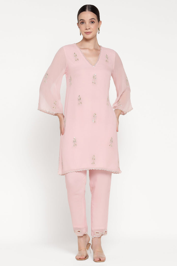 Woman wearing a light pink traditional outfit with a plain background