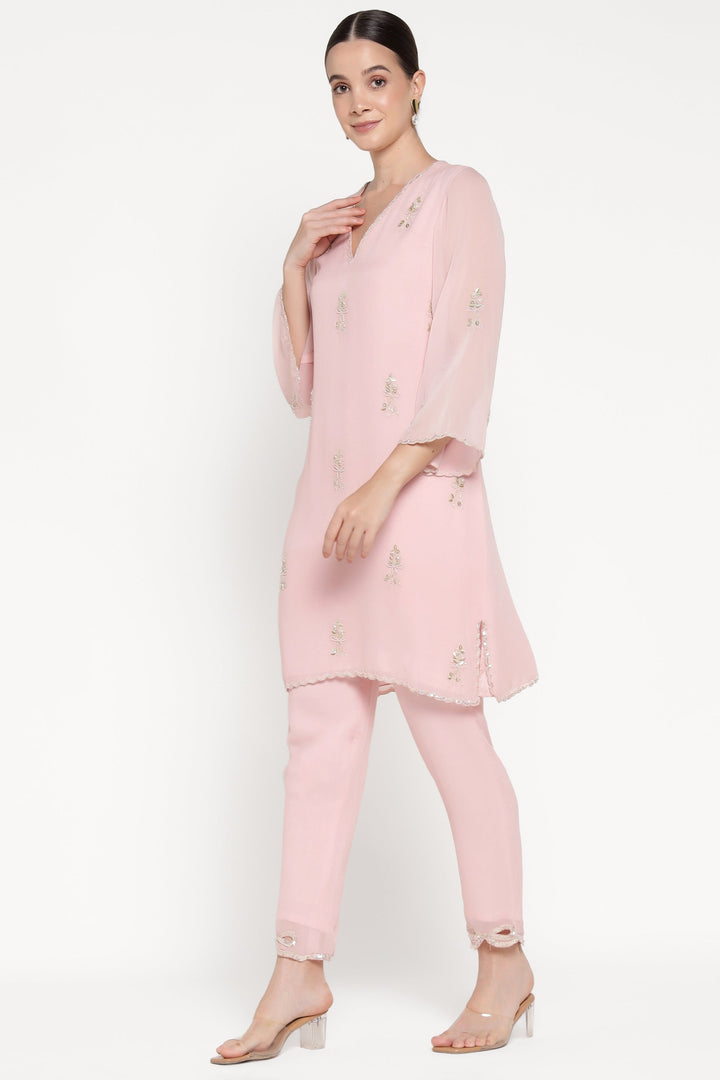 Woman wearing a pink outfit with a top and pants on a white background