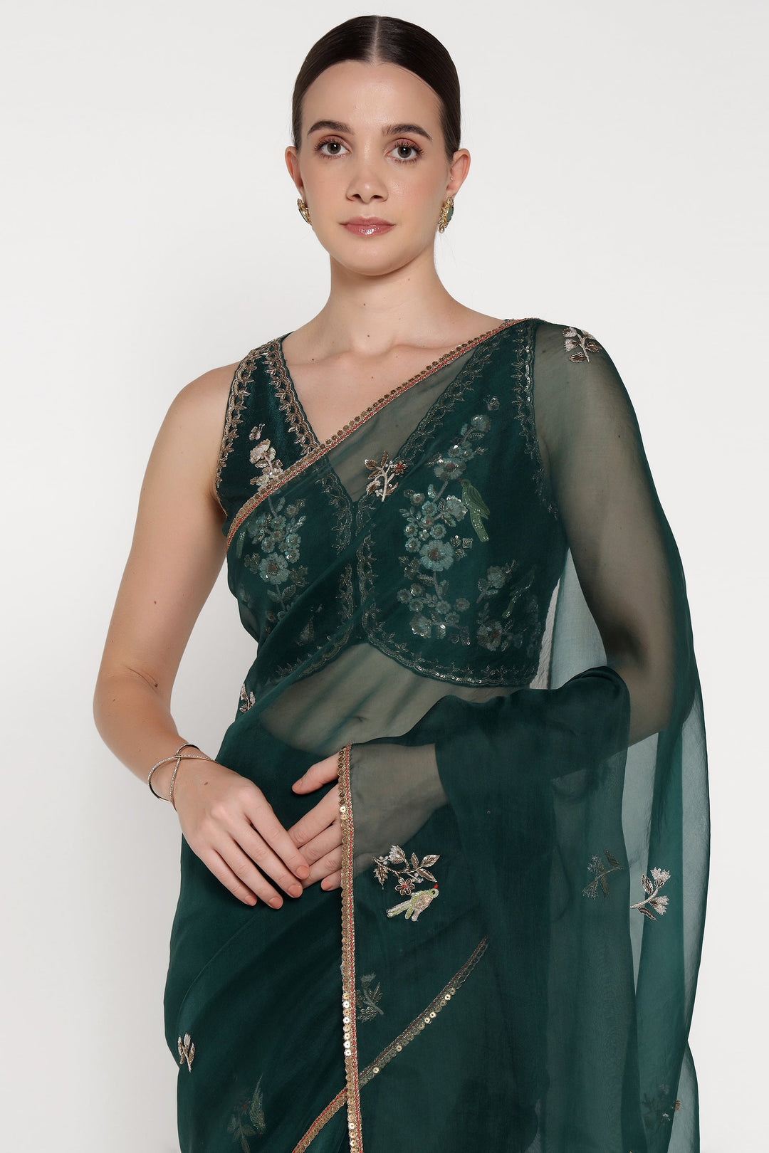 Woman wearing a dark green saree with floral embroidery on a white background