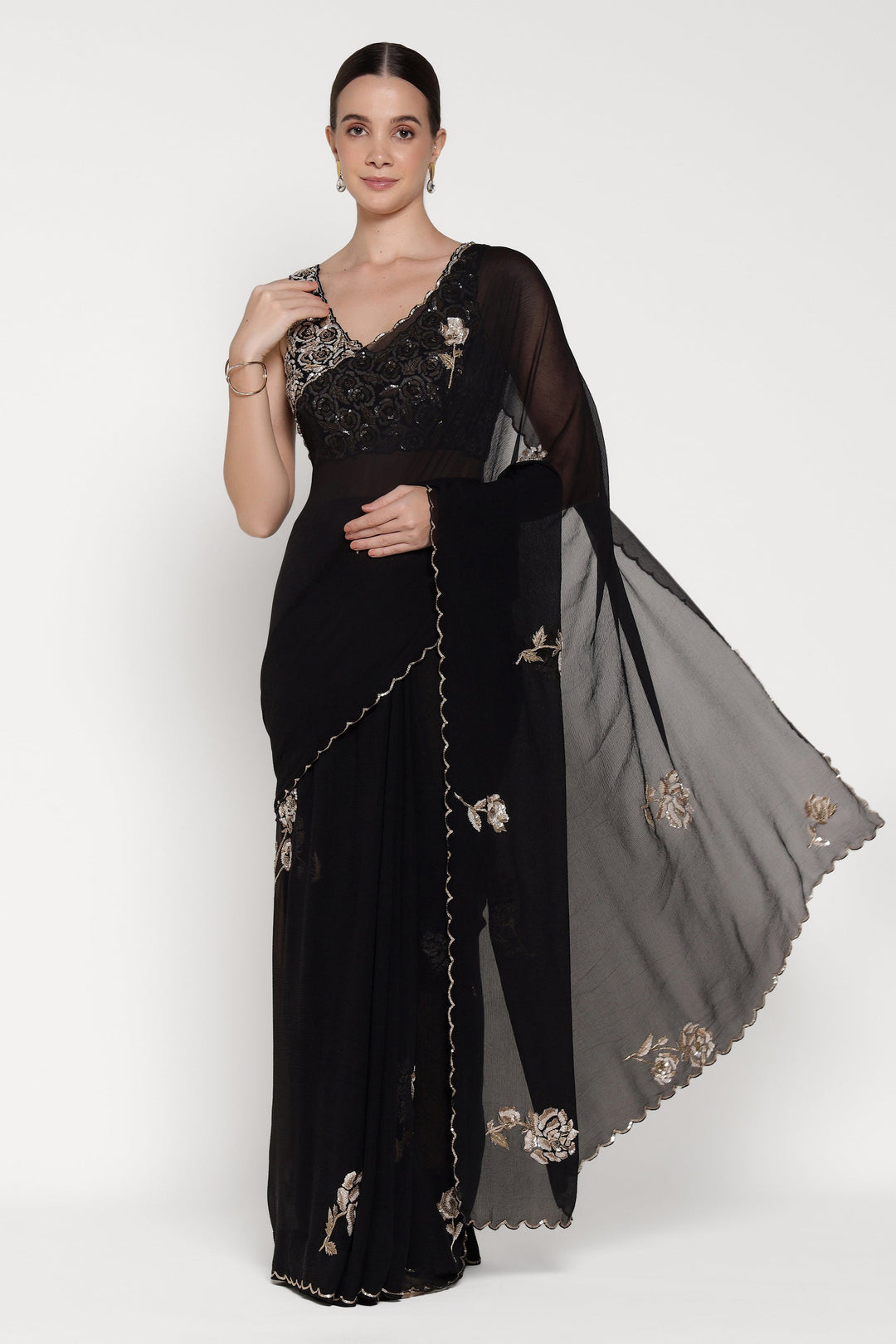 Woman wearing a black saree with floral embroidery on a white background