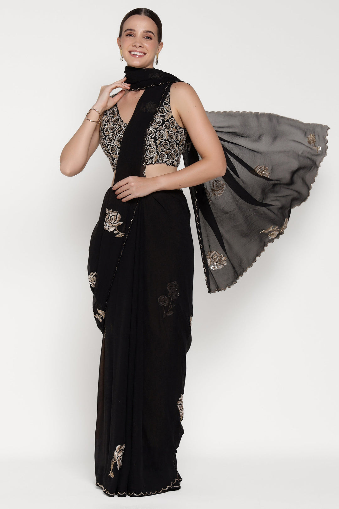 Woman wearing a black saree with gold embroidery on a white background