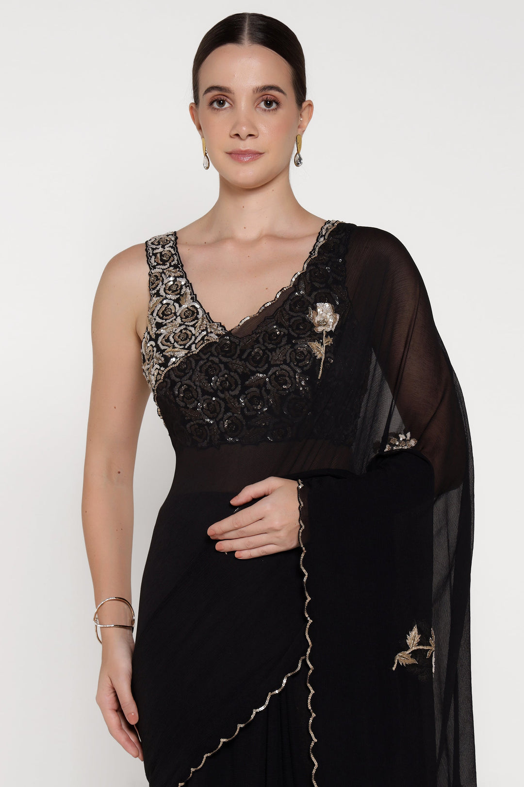 Woman wearing a black saree with intricate designs on a white background