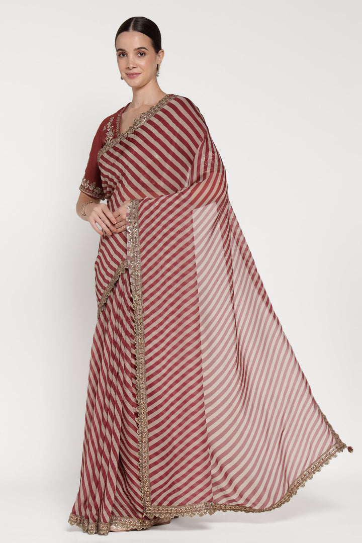 Woman wearing a red and white striped saree with a plain background
