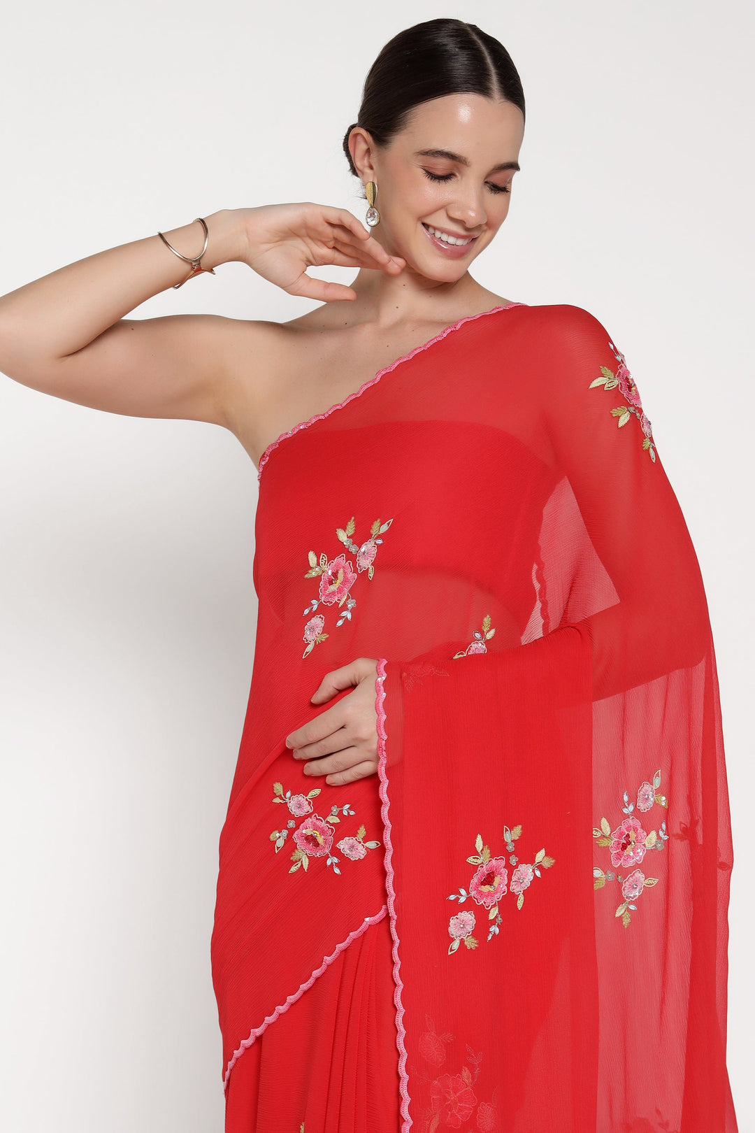 Woman wearing a red saree with floral embroidery on a white background