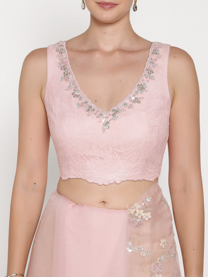 Pink lace top with floral embellishments on a plain background