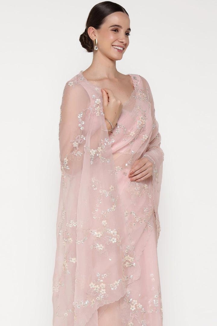 Woman wearing a light pink floral dress against a white background