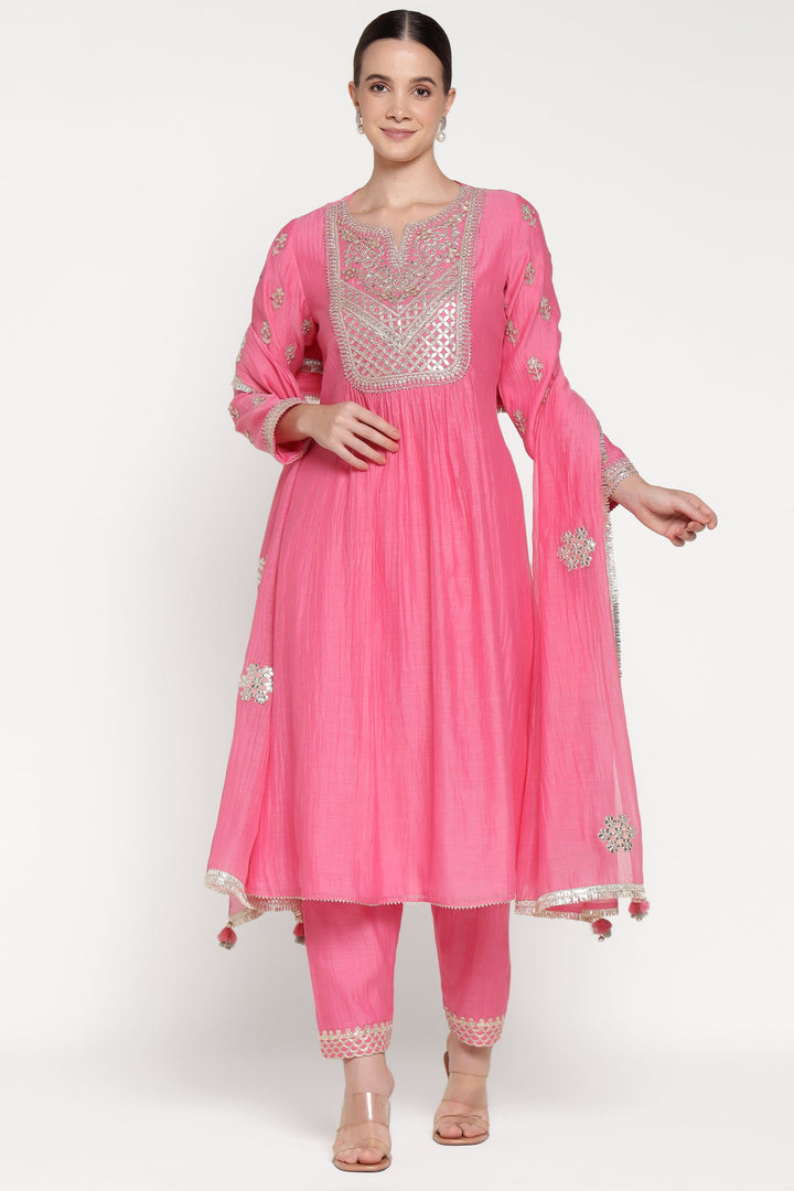 Woman wearing a pink traditional outfit with intricate designs on a white background