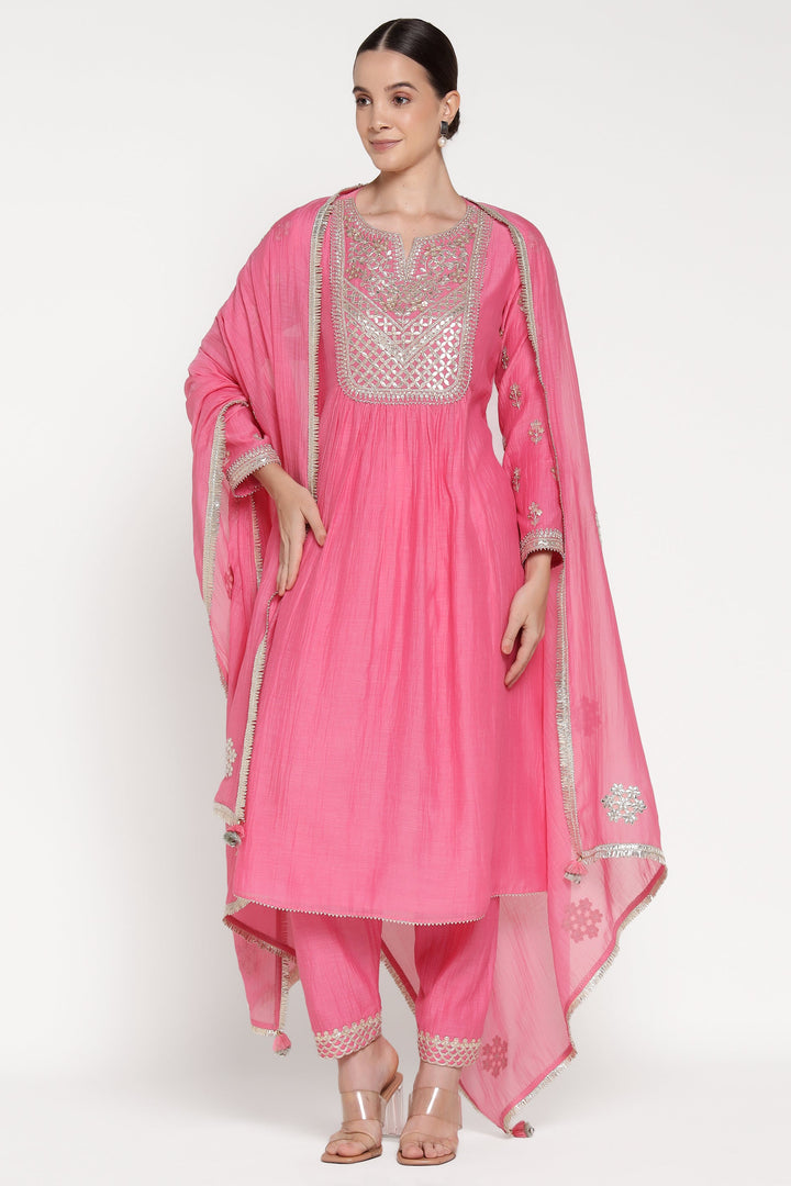 Woman wearing a pink traditional outfit with silver embroidery on a white background