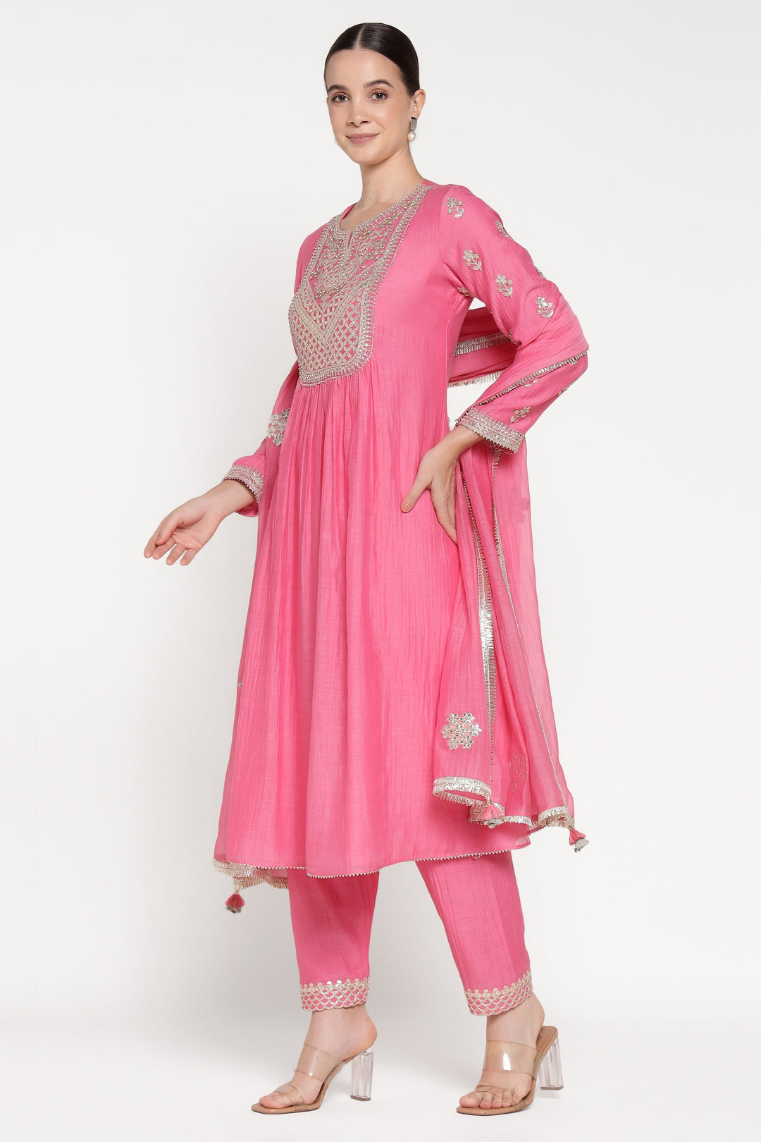 Woman wearing a pink traditional outfit with intricate designs on a white background