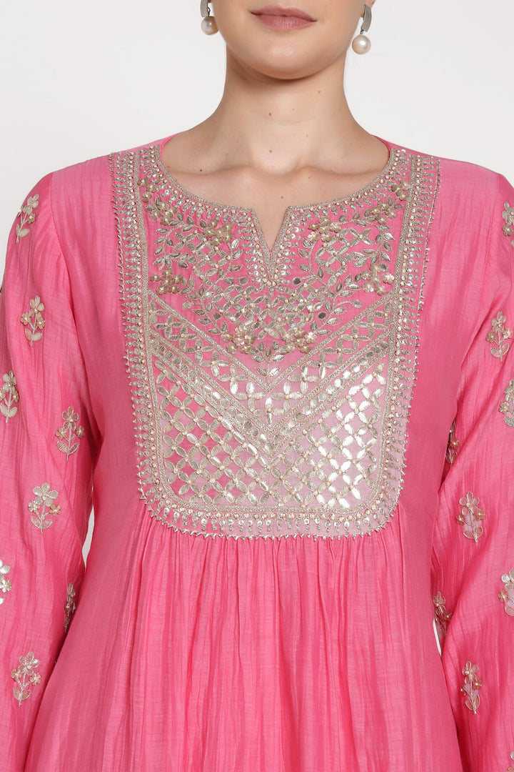 Pink traditional outfit with intricate silver embroidery on a plain background